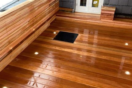 Strategically placed floor spotlights illuminating a cedar roof terrace, creating a warm and inviting ambiance for nighttime entertaining.