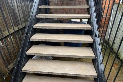 An elevated landing and custom metal staircase creating a seamless and elegant transition to the building's interior.