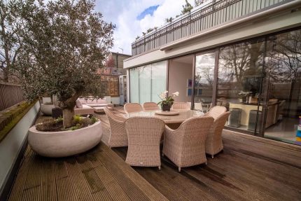 A beautiful terrace roof in Kensington adorned with exquisite hard wood decking and an array of lush plants.