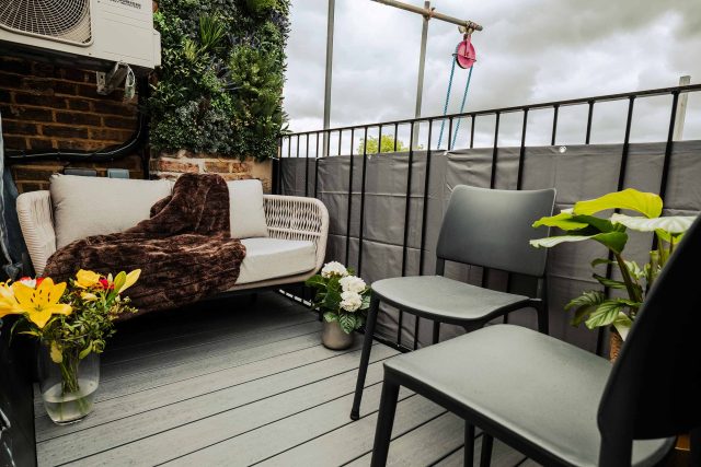Refurbished apartment balcony with glass balustrades and outdoor seating