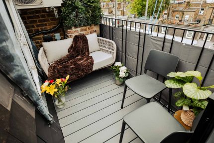 Chimney breast clad in UV-resistant, ultra-realistic artificial foliage to enhance a small rooftop balcony.