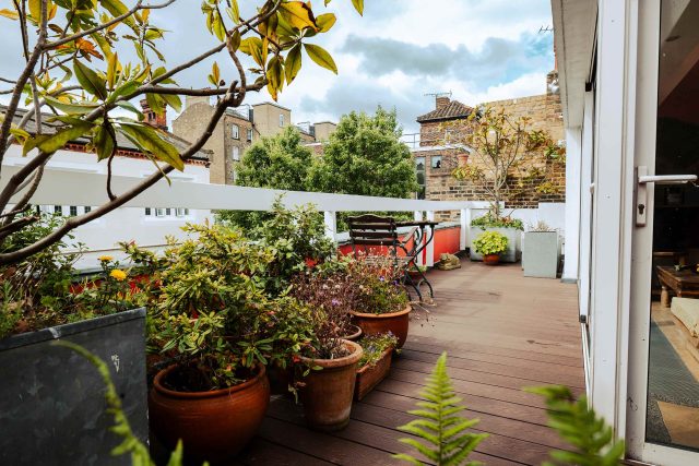 Timber decking supporting appropriately weighted plant pots and vibrant flora on a residential roof garden terrace.