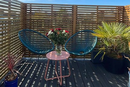 Grey composite decking features alongside a bespoke privacy screen and integrated seating in this complete flat roof conversion.