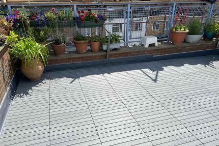 High-grade grey composite decking tiles protecting the underlying membrane on a residential flat roofing London domestic upgrade.