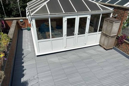 Durable grey composite decking expertly fitted by our roofer London contractors around a traditional Kingston conservatory structure.
