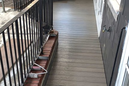 Narrow composite decking boards running parallel to modern iron balustrades during a bespoke balcony renovation in West Hampstead.
