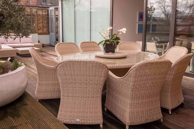 A contemporary wicker dining set rests on premium wooden decking within a modern London roof terrace design.