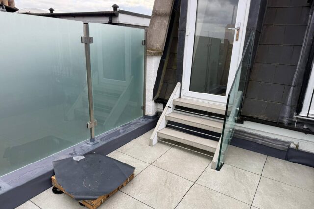 Newly constructed contemporary roof terrace in Battersea, London, featuring high-quality paving slabs and glass balustrades.