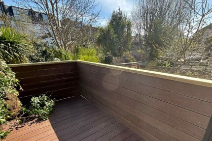 Fully accredited flat roofer London portfolio installation demonstrating precision alignment of sustainable composite decking and safety fencing.