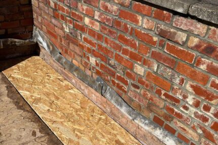 Traditional lead flashing seamlessly integrated with a modern flat roofing London system against a classic brick boundary wall.