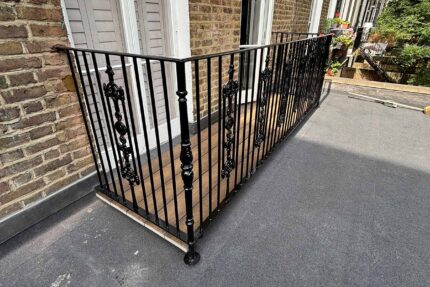 Structural timber decking and robust black metal railings completing a high-end balcony upgrade by a specialist roofer London contractor.