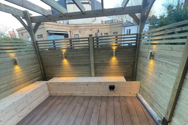 Bespoke residential roof garden featuring a custom pergola, slatted privacy fencing, and integrated bench seating installed over premium Millboard decking.