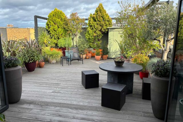 Premium residential flat roof conversion installed by our expert flat roofer team in Shoreditch, London, featuring eco-friendly grey composite decking and an al-fresco outdoor dining setup.