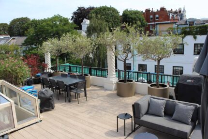 High-specification composite decking provides a durable, slip-resistant foundation for a modern outdoor dining and seating arrangement on a London penthouse terrace.