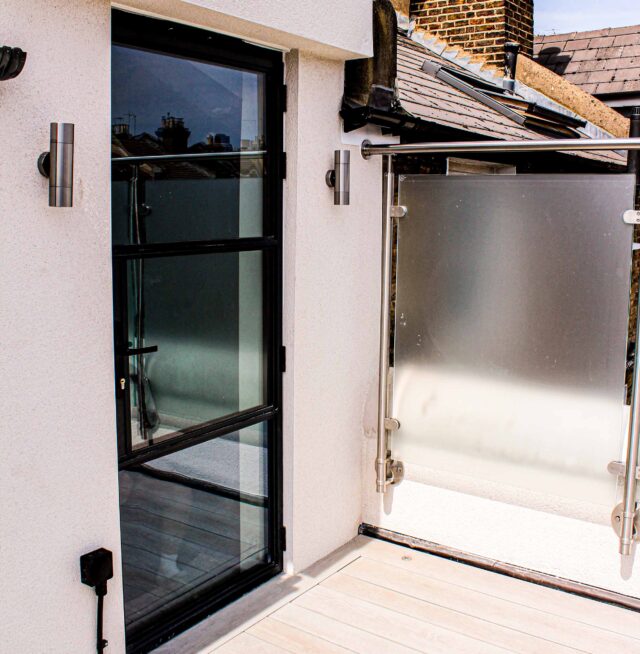 Frosted glass privacy balustrades and modern black framed aluminium access doors define this premium flat roofing London conversion in Vauxhall.