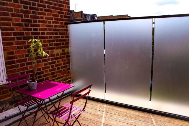 Premium Millboard composite decking and bespoke opaque glass screens define this flat roofing London terrace conversion in Parsons Green.