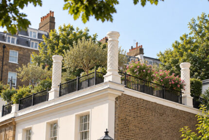 HA modern townhouse rooftop garden enclosed by metal railings, featuring bespoke built-in planters.