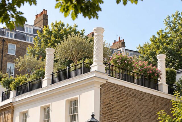 A modern rooftop garden terrace on a stucco townhouse, featuring custom planters and sleek metal railings.